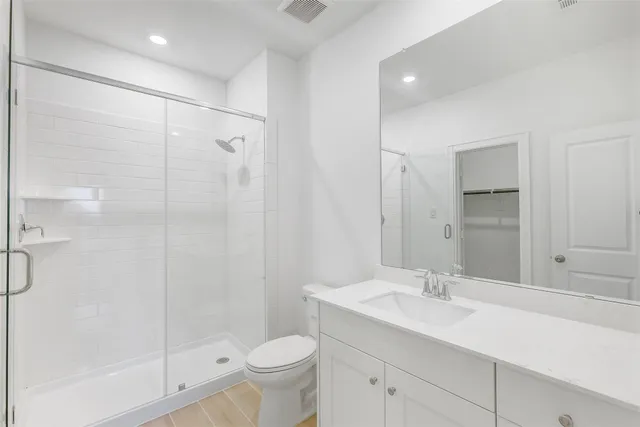 a bathroom with a shower sink vanity mirror and toilet