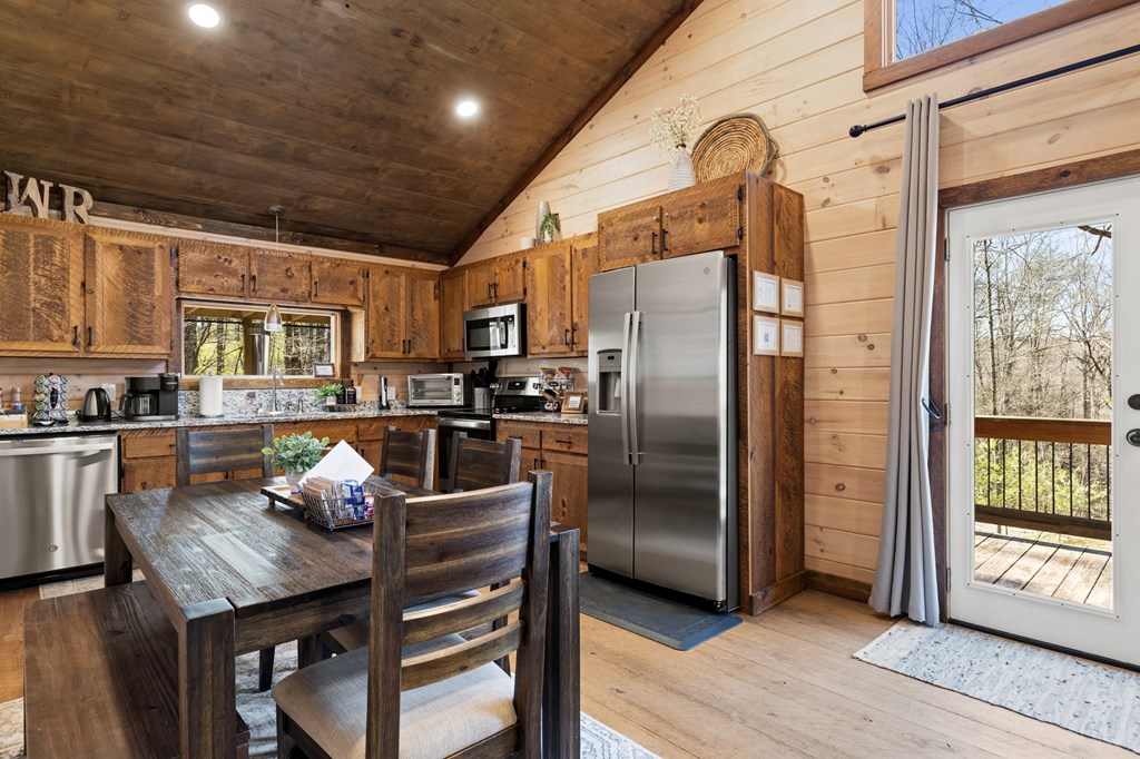 941 Hidden Valley Drive Morganton, GA 30560 - Photo 18 of 35 a kitchen with stainless steel appliances granite countertop a refrigerator a stove a sink a dining table and chairs with wooden floor