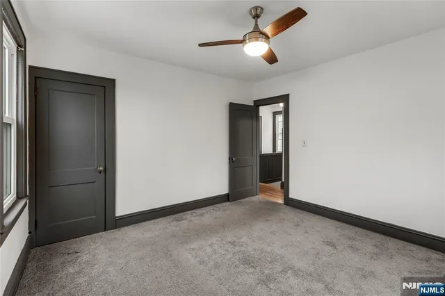 an empty room with ceiling fan and windows