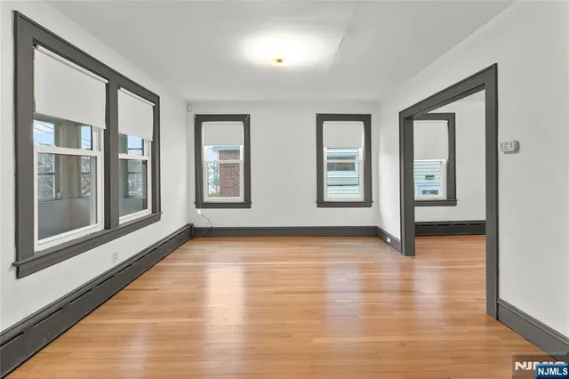 a view of an empty room with window and wooden floor