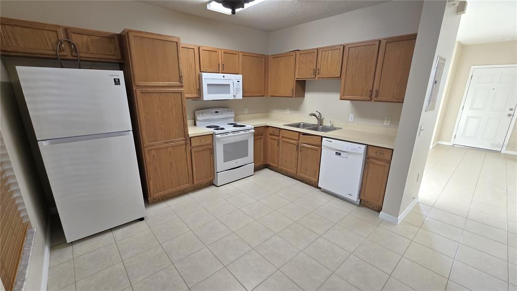 1302 Denman Court Wesley Chapel, FL 33543 - Photo 11 of 28 a kitchen with a refrigerator sink stove and cabinets