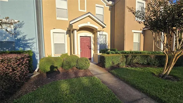 a view of a house with a small yard plants and large tree