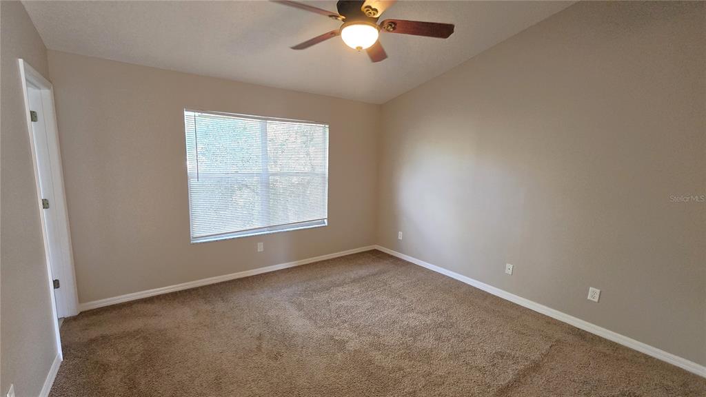 1302 Denman Court Wesley Chapel, FL 33543 - Photo 23 of 28 an empty room with a window and a chandelier fan
