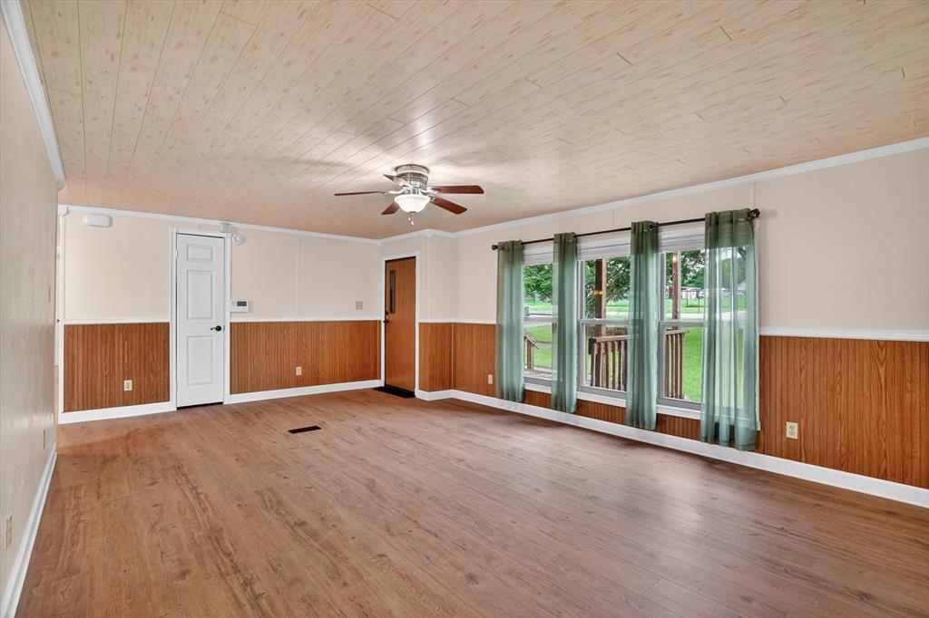 7757 Berry Road Burleson, TX 76028 - Photo 14 of 36 Spacious room featuring wood-finish flooring, half-wall wood paneling, and a wood-paneled ceiling