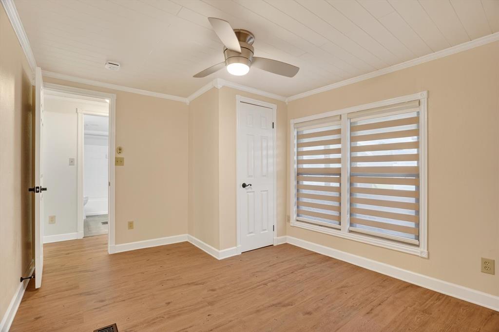 7757 Berry Road Burleson, TX 76028 - Photo 18 of 36 Room featuring wood-finish flooring, two large windows with horizontal blinds, a ceiling fan with integrated lighting, and crown molding