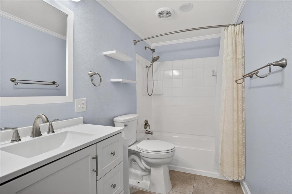 7757 Berry Road Burleson, TX 76028 - Photo 19 of 36 Bathroom featuring a white vanity with integrated sink, brushed nickel fixtures, a framed mirror, and a full-sized tub with shower