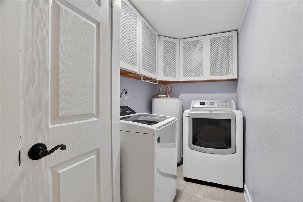 7757 Berry Road Burleson, TX 76028 - Photo 20 of 36 Functional utility room featuring upper cabinetry with textured panel doors, light wall paint, and durable tile flooring