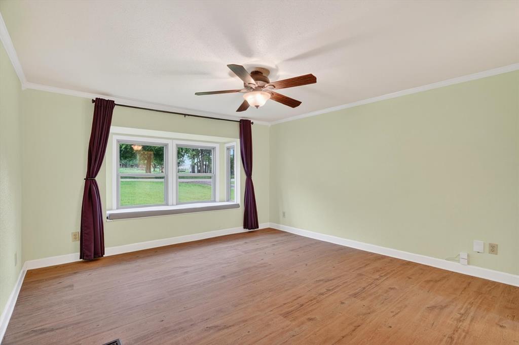 7757 Berry Road Burleson, TX 76028 - Photo 21 of 36 Spacious room featuring wood-finish flooring, a multi-pane bay window, and a ceiling fan with integrated lighting