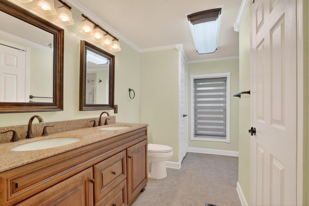 7757 Berry Road Burleson, TX 76028 - Photo 22 of 36 Double vanity featuring wood cabinetry, integrated sinks, bronze hardware, and a speckled countertop