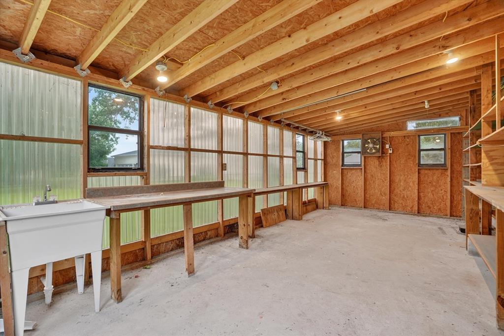 7757 Berry Road Burleson, TX 76028 - Photo 27 of 36 Versatile shop featuring exposed wood beam ceiling, concrete flooring, built-in workbench, utility sink, and ample natural light from multiple windows
