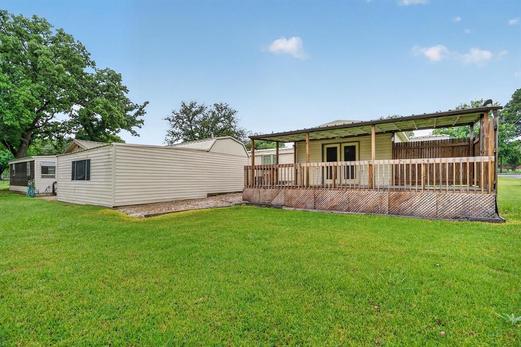 7757 Berry Road Burleson, TX 76028 - Photo 29 of 36 Expansive backyard featuring a covered wood deck with privacy lattice, a detached storage building, and additional outbuilding