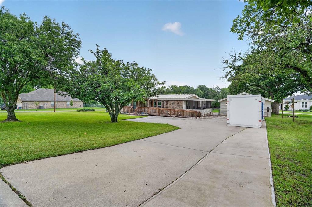 7757 Berry Road Burleson, TX 76028 - Photo 5 of 36 Concrete driveway leading to a residence with a covered porch and wood decking