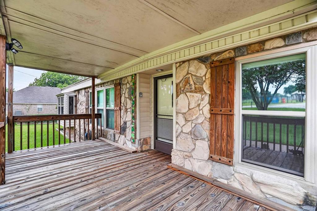 7757 Berry Road Burleson, TX 76028 - Photo 7 of 36 Covered front porch featuring wood-finish decking, stone facade accents, decorative wood shutters, and durable vinyl siding