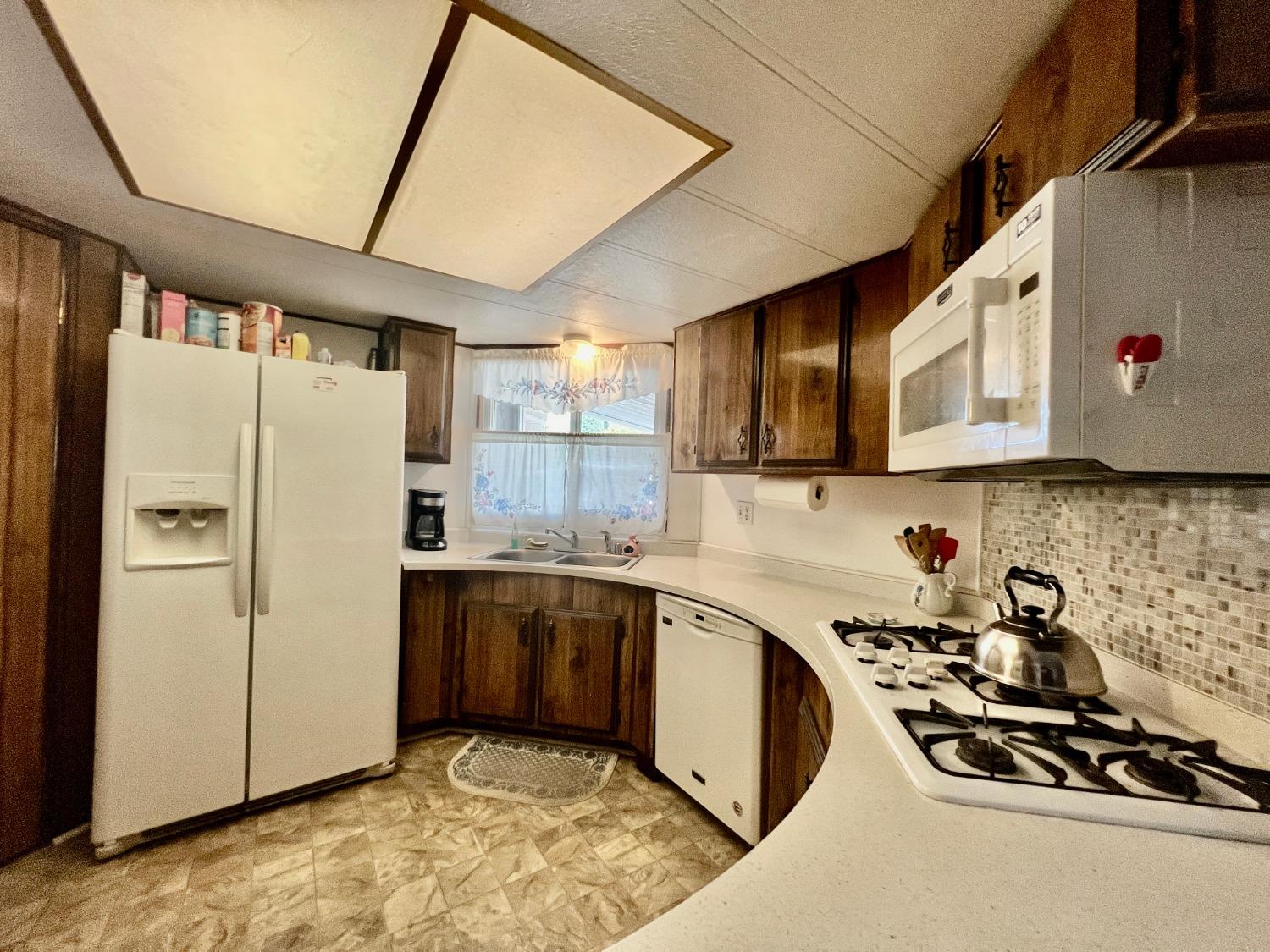 6008 Cackler Lane, Unit 88 Citrus Heights, CA 95621 - Photo 3 of 21 a kitchen with stainless steel appliances granite countertop a refrigerator a sink dishwasher a stove with wooden cabinets