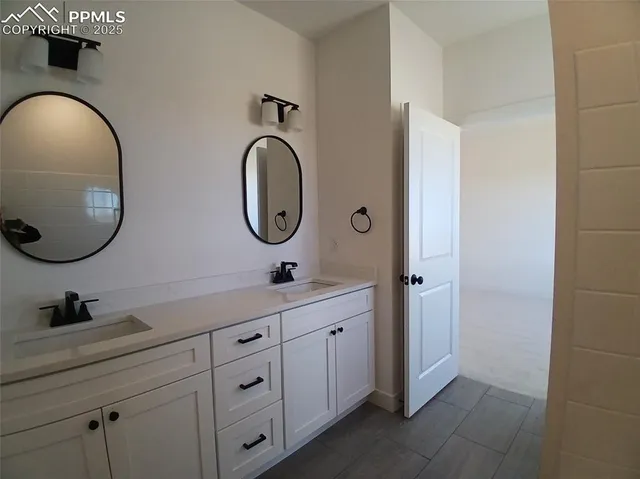 a bathroom with a granite countertop double vanity sink and a mirror