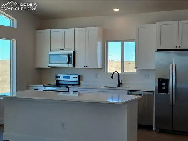 a kitchen with stainless steel appliances granite countertop a sink a refrigerator and a granite counter tops