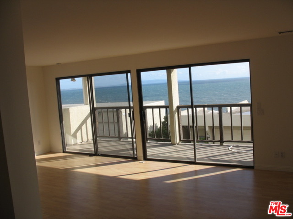 18057 Coastline Drive, Unit 5 Malibu, CA 90265 - Photo 13 of 21 a view of empty room with wooden floor and floor to ceiling window