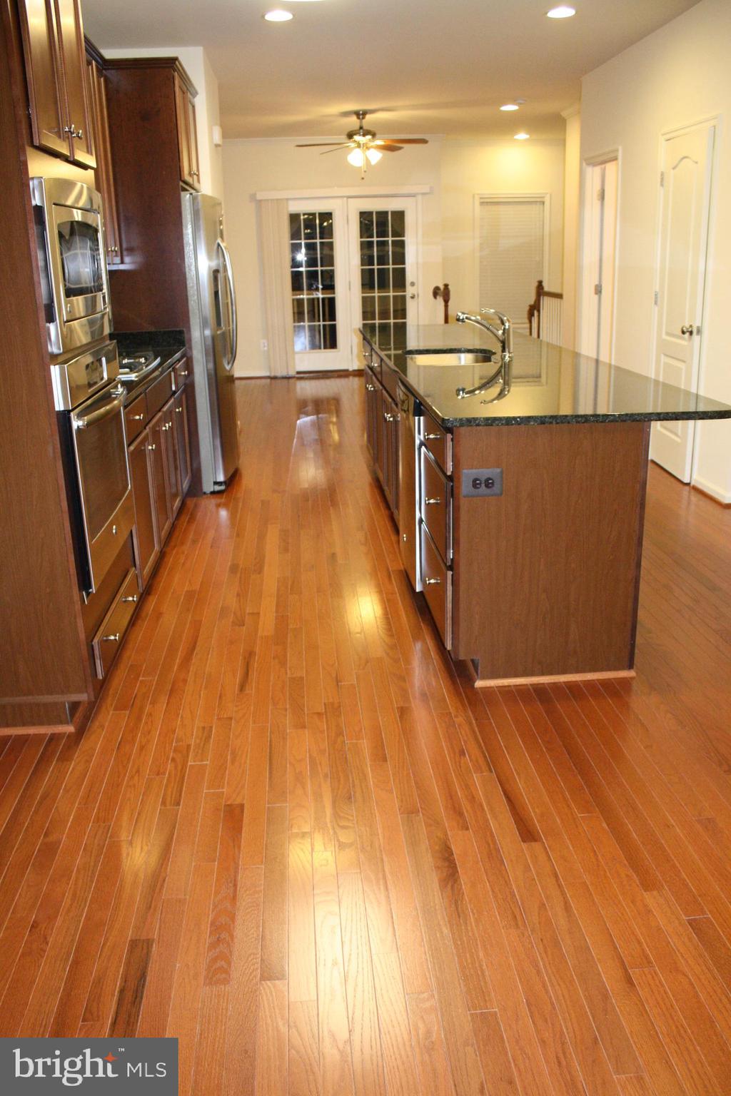 a kitchen with stainless steel appliances wooden floor and large windows