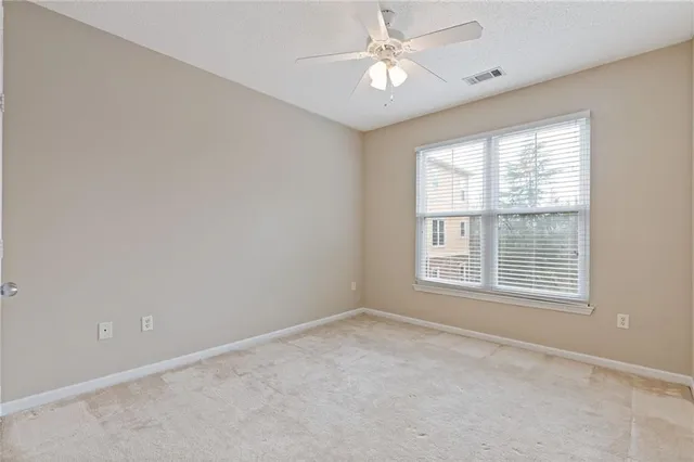 an empty room with a window and a ceiling fan