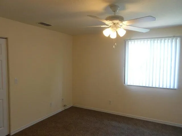 an empty room with a window and a chandelier fan