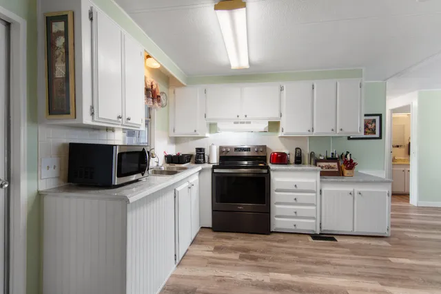a kitchen with stainless steel appliances granite countertop a stove a sink and white cabinets