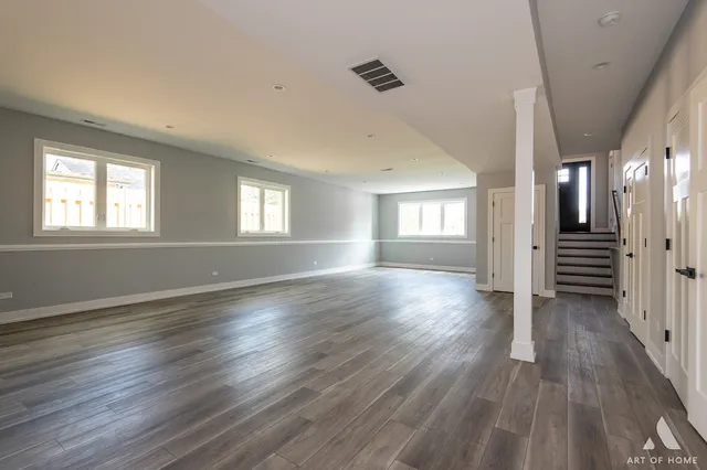 an empty room with wooden floor ceiling fan and windows
