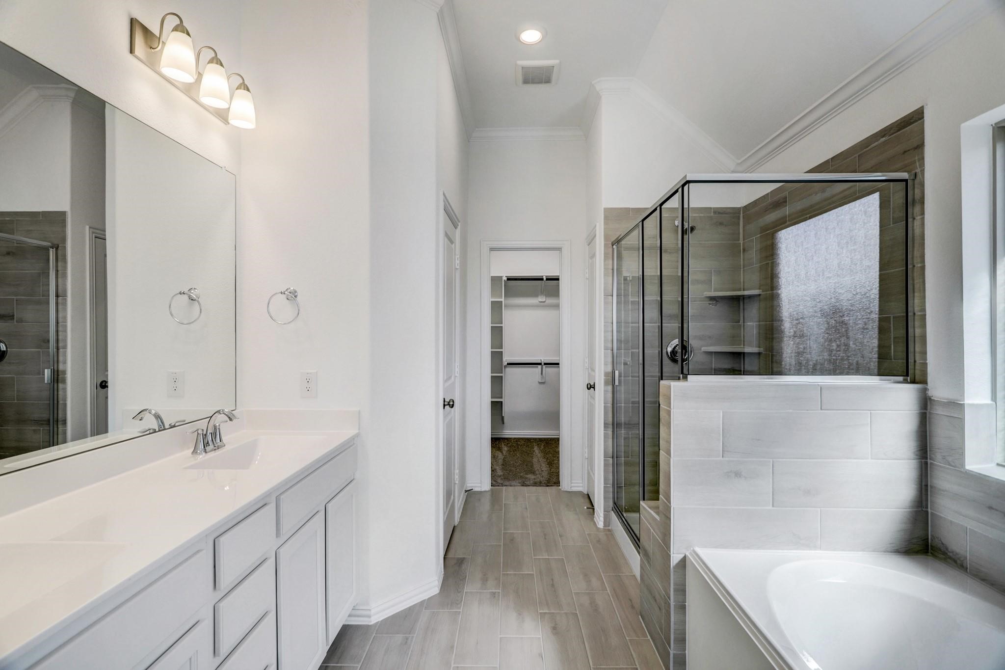 21015 Morning Nectar Lane Cypress, TX 77433 - Photo 13 of 34 a bathroom with a double vanity sink a large mirror and a bathtub