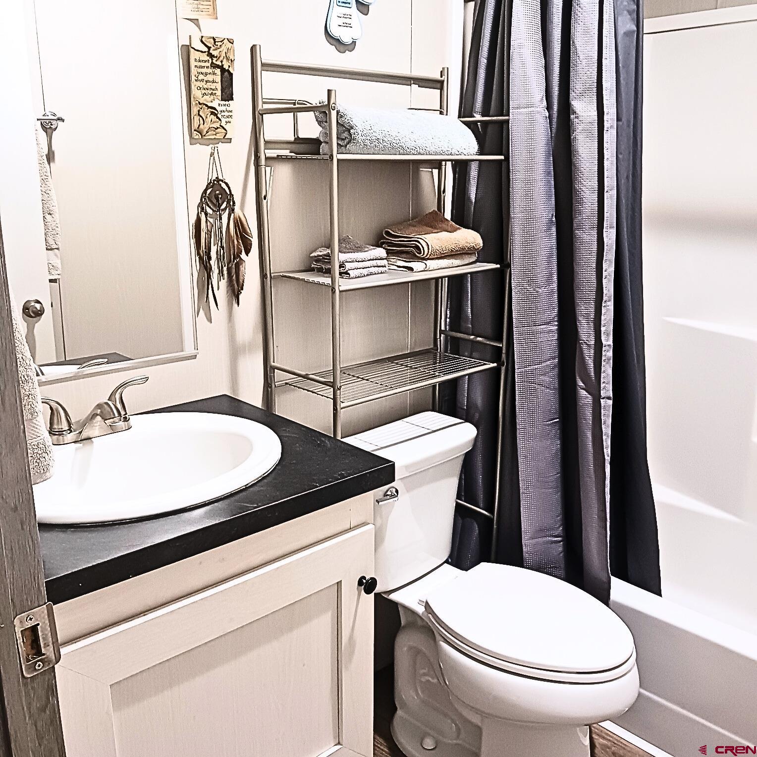 62650 Lasalle Road, Unit 317 Montrose, CO 81403 - Photo 4 of 23 a bathroom with a granite countertop toilet sink and mirror