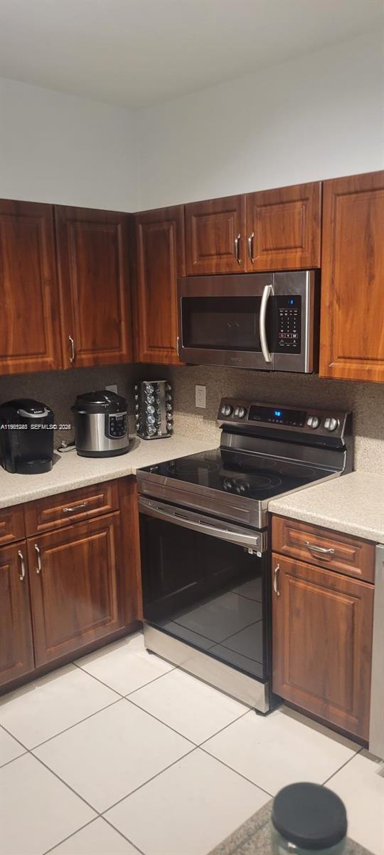 8331 Southwest 124th Avenue, Unit 10114 Miami, FL 33183 - Photo 18 of 19 a kitchen with granite countertop a stove top oven microwave and cabinets