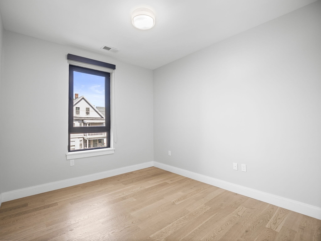9 Central Street, Unit 207 Somerville, MA 02143 - Photo 12 of 32 an empty room with wooden floor and window