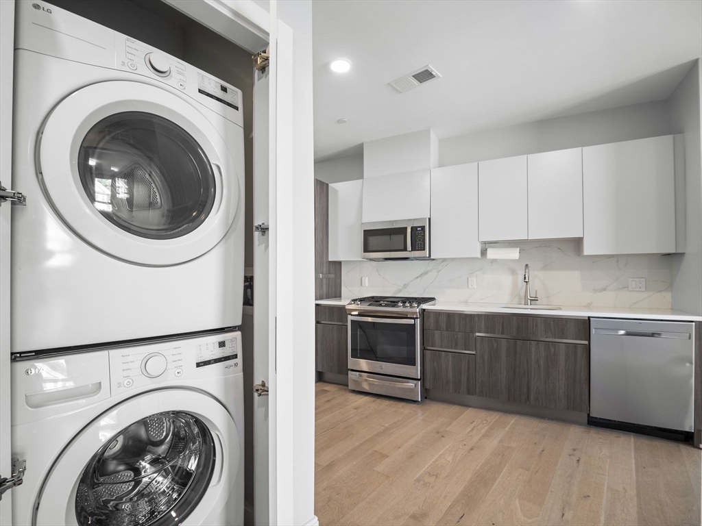 9 Central Street, Unit 207 Somerville, MA 02143 - Photo 15 of 32 a large white kitchen with stainless steel appliances granite countertop a stove a sink and a refrigerator