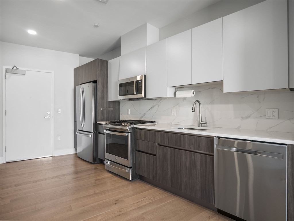 9 Central Street, Unit 207 Somerville, MA 02143 - Photo 4 of 32 a kitchen with wooden cabinets and stainless steel appliances