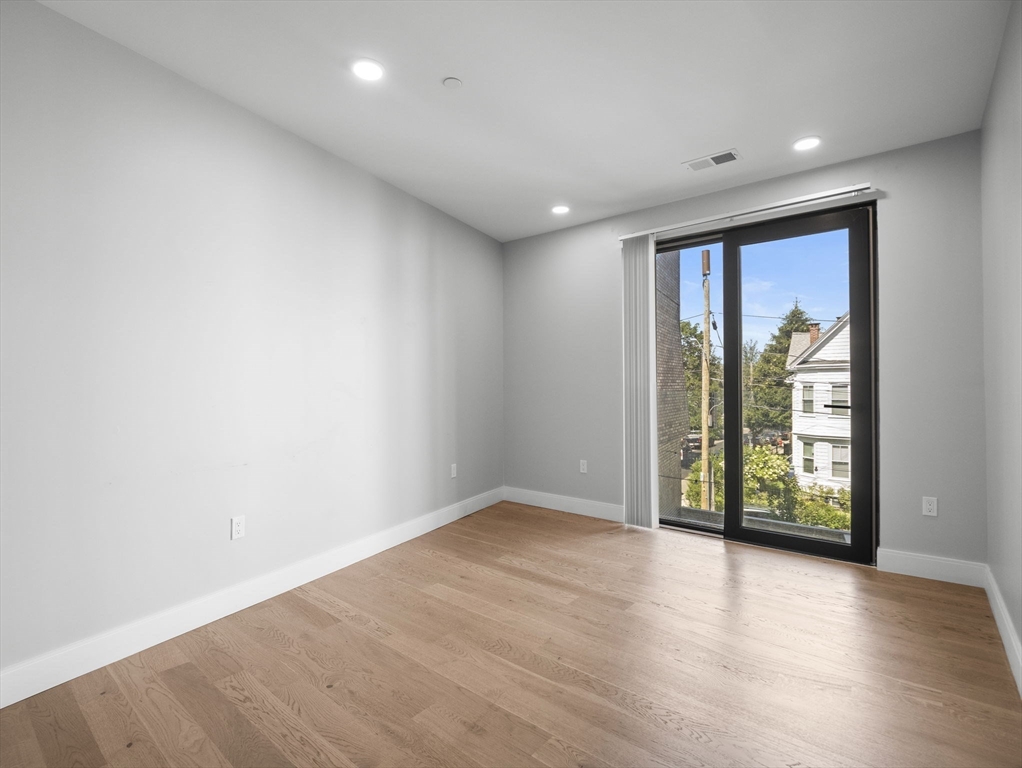 9 Central Street, Unit 207 Somerville, MA 02143 - Photo 7 of 32 an empty room with wooden floor and windows