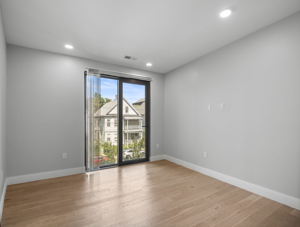 9 Central Street, Unit 207 Somerville, MA 02143 - Photo 9 of 32 an empty room with wooden floor and balcony