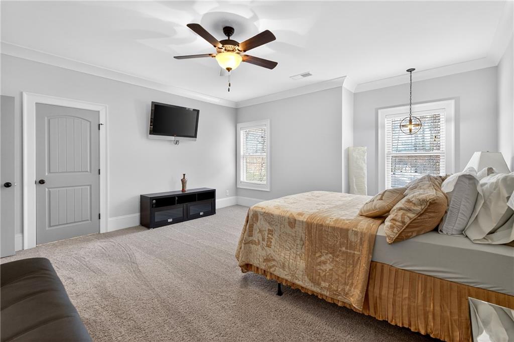 3944 Hamilton Mill Road Buford, GA 30519 - Photo 40 of 55 a bedroom with a large bed a flat tv screen and a ceiling fan