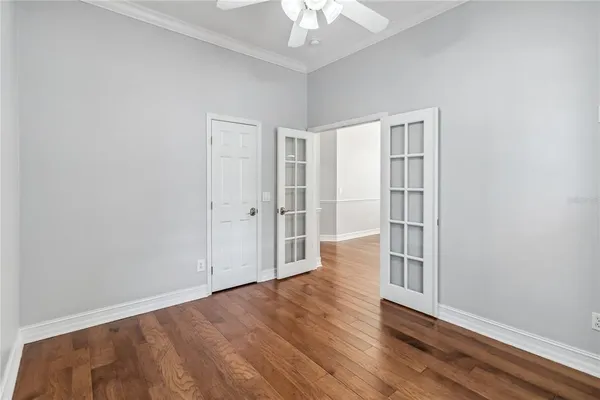 an empty room with wooden floor chandelier fan and windows