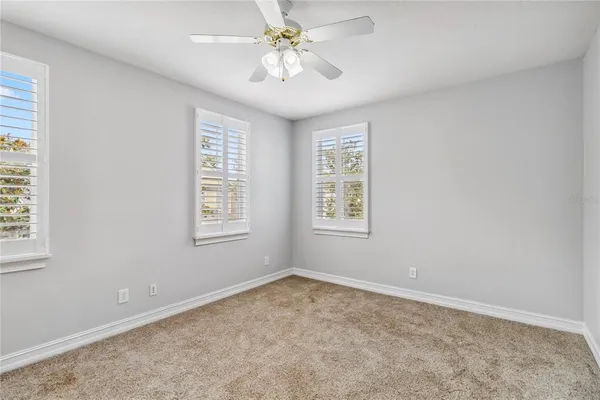 an empty room with windows and fan