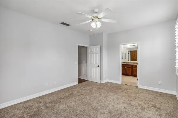 a view of an empty room with chandelier fan