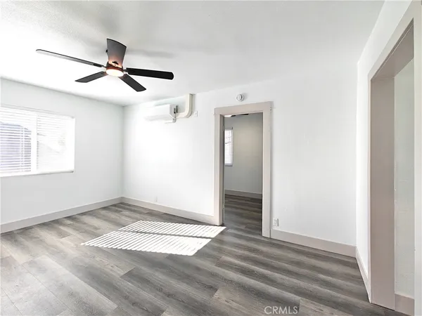 an empty room with wooden floor ceiling fan and windows