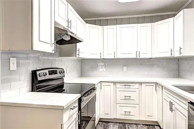a kitchen with stainless steel appliances white cabinets and a window