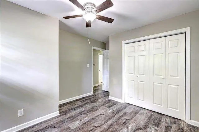 an empty room with wooden floor closet and windows