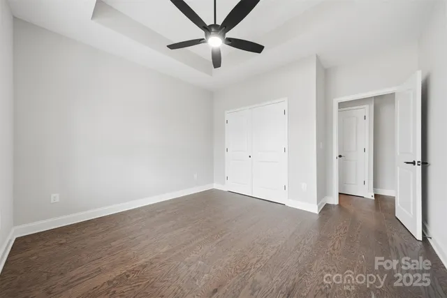 an empty room with wooden floor and a ceiling fan