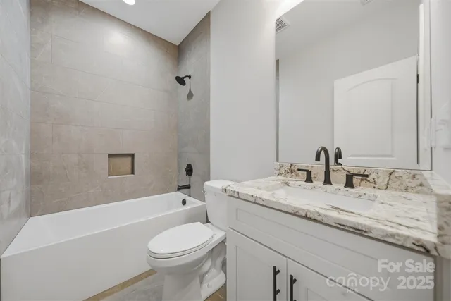 a bathroom with a granite countertop sink toilet mirror and bathtub