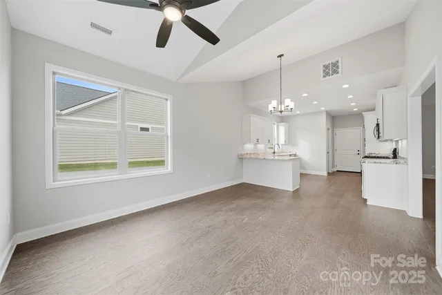 a view of an empty room with kitchen and window