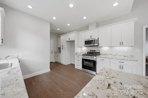 a kitchen with granite countertop white cabinets and stainless steel appliances