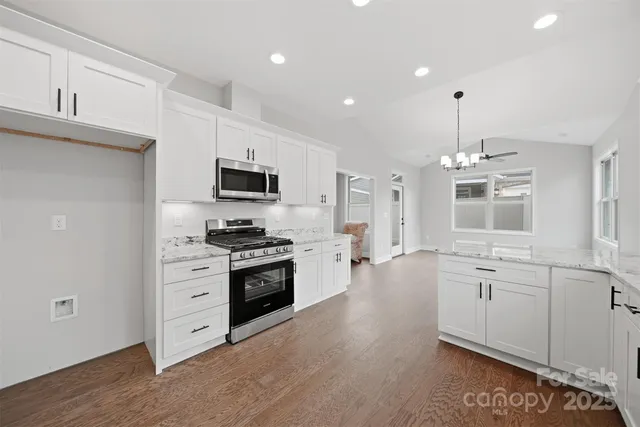 a large kitchen with stainless steel appliances granite countertop a stove and a sink