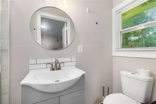 a bathroom with a sink a mirror a toilet and a window