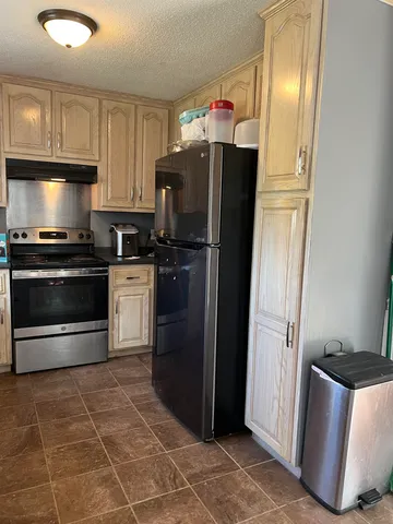 a kitchen with granite countertop a refrigerator stove and sink