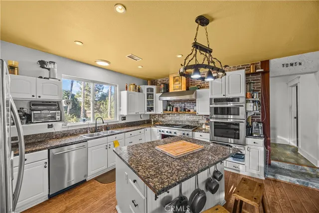 a utility room with stainless steel appliances kitchen island granite countertop a sink and a refrigerator