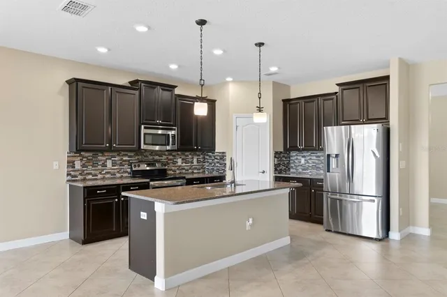 a kitchen with kitchen island granite countertop a sink a counter space appliances and cabinets